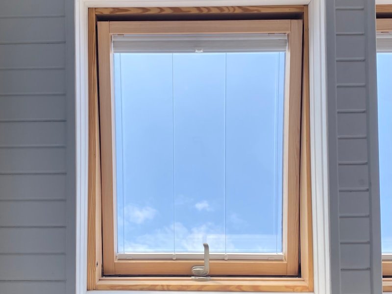 A newly set window unit finished into siding under a clear sky